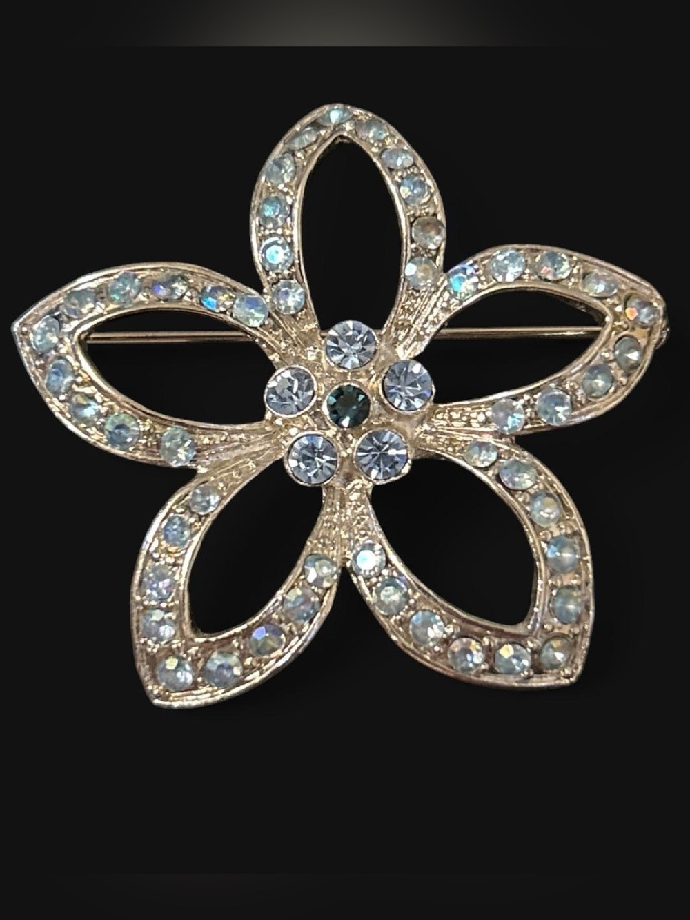 Silver tone flower brooch with blue rhinestones